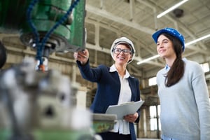 Two women discussing manufacturing equipment and capital efficiency.