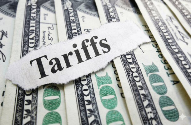 A torn piece of paper with the word "Tariffs" in black serif font is placed over a stack of hundred-dollar bills.