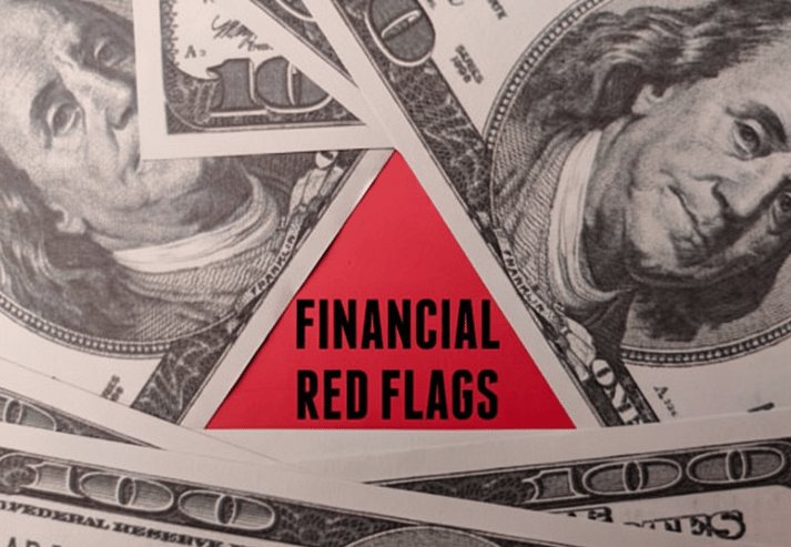A red triangle with the words "FINANCIAL RED FLAGS" in black text is centered on the image, surrounded by a fan of hundred-dollar bills.