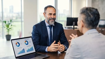 two business men talking about business strategy with a laptop open with graphs on screen 